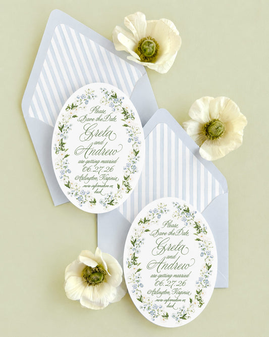 Luxury oval save the date with a hand-painted blue floral watercolor border, elegant green typography, and a powder blue envelope with coordinating watercolor striped liner for garden and coastal weddings